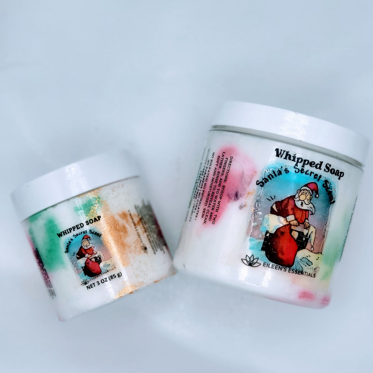 Small and large Santa's Secret Scent whipped soap jars tilted side by side on a light background.